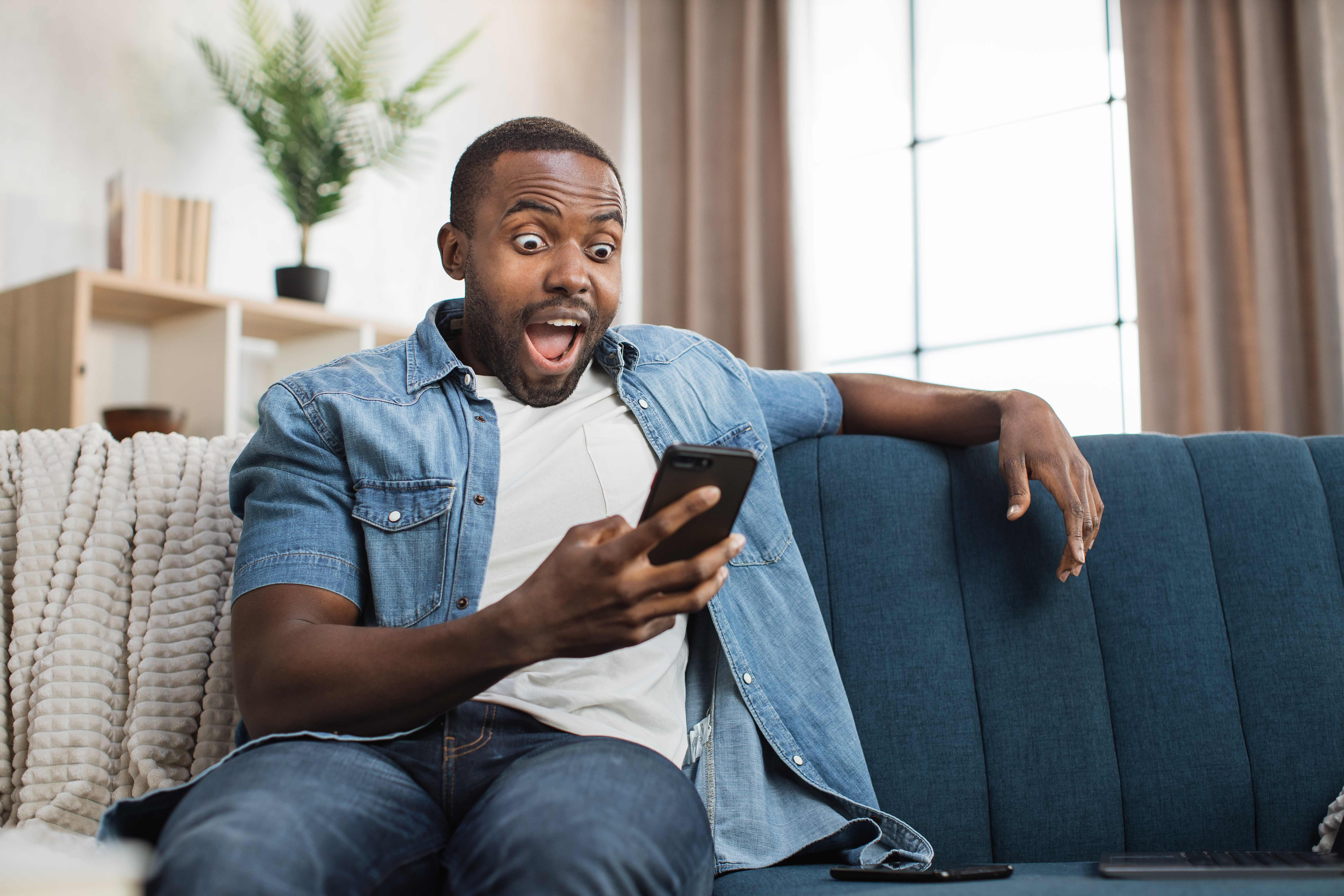 African man reading good news on mobile at home